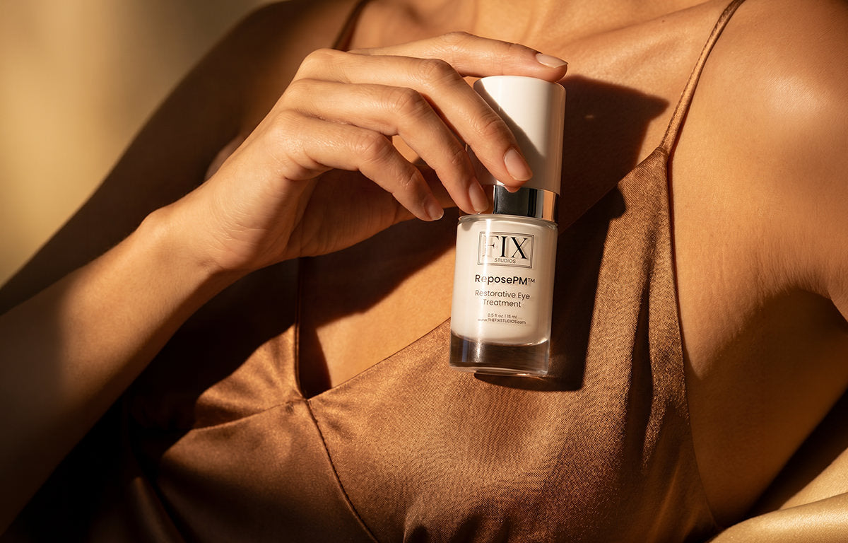 A woman holds a bottle of Fix Studios Medical-Grade ReposePM™ Restorative Eye Treatment while wearing her night gown, it is silky smooth and non-greasy
