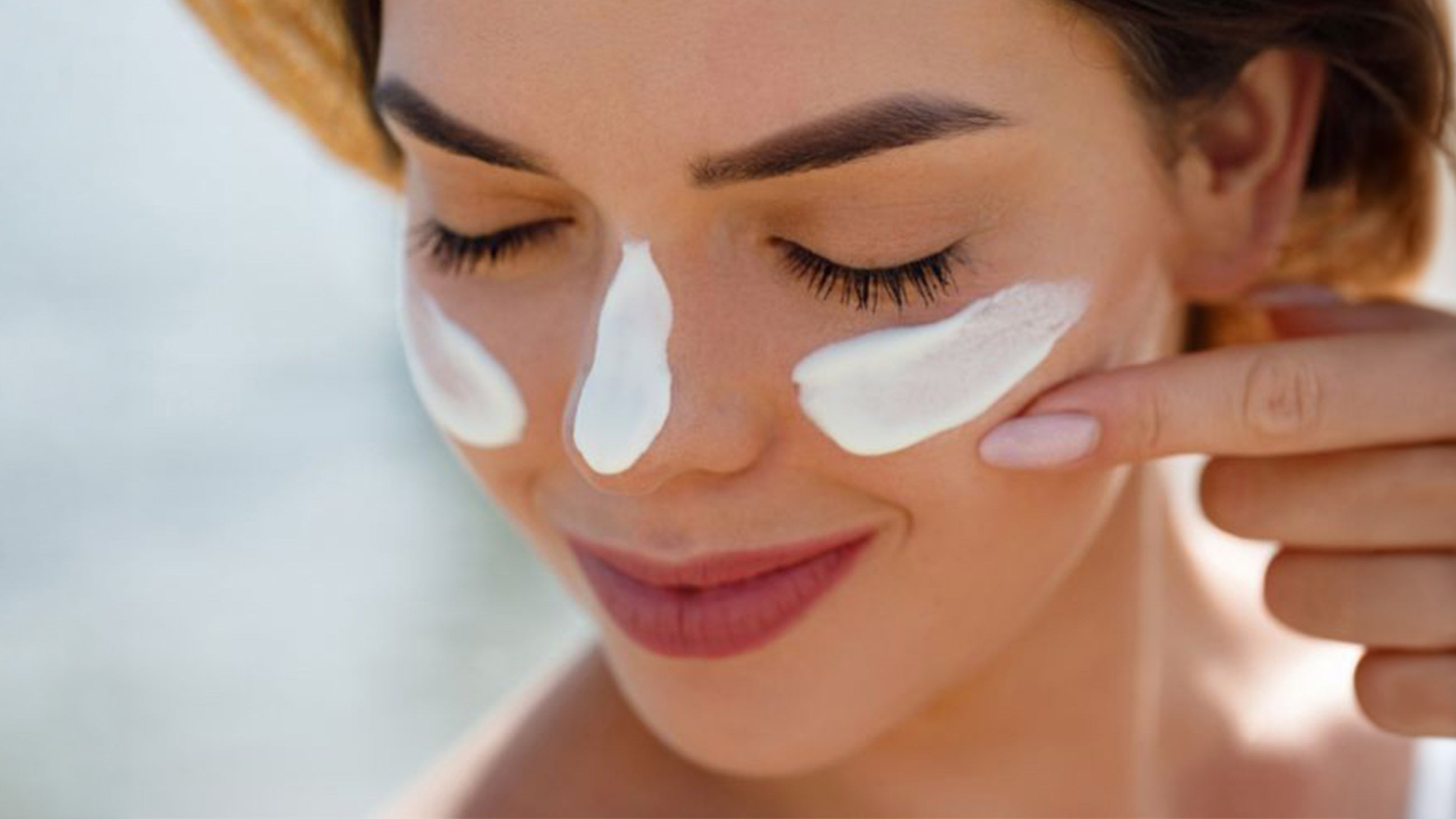 A woman applies SPF to her face