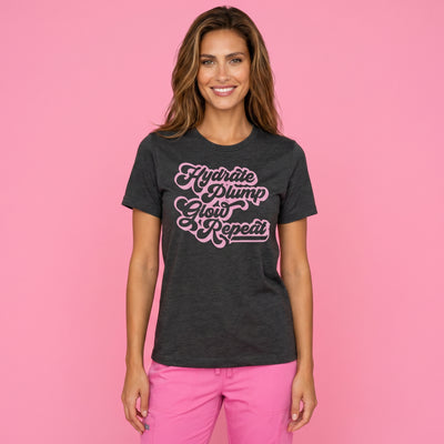 A woman on a pink background wearing Fix Studios Hydrate Plump Glow Repeat t-shirt for medspa professionals, injectors and Botox/medspa fans