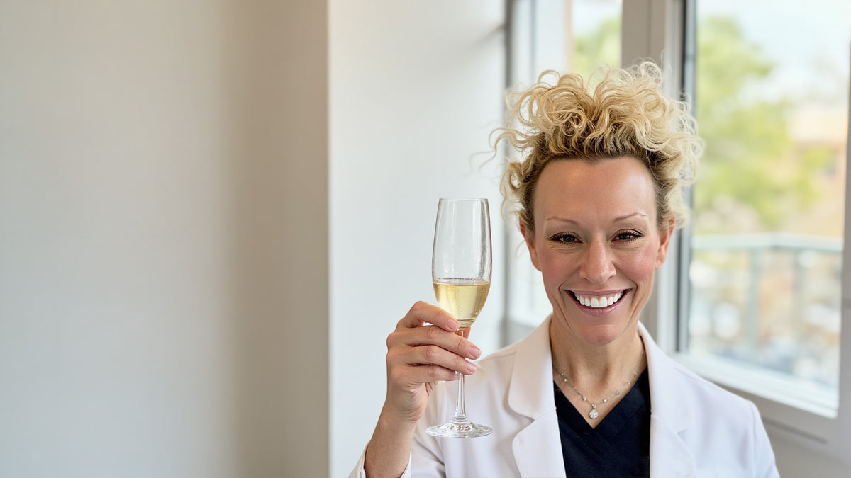 Dr Beth Matre holds a glass of champaign to toast the annual Fix Studios Signature Sales Event