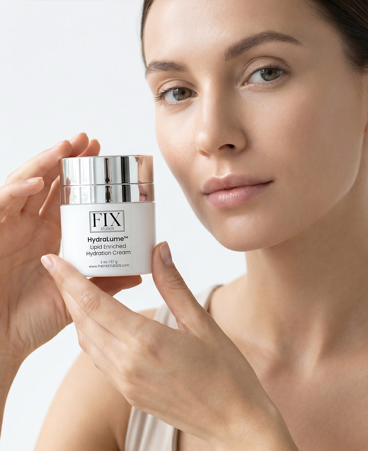 Close up of a woman holding  Fix Studios medical-grade HydraLume™ Lipid Enriched Hydration Cream