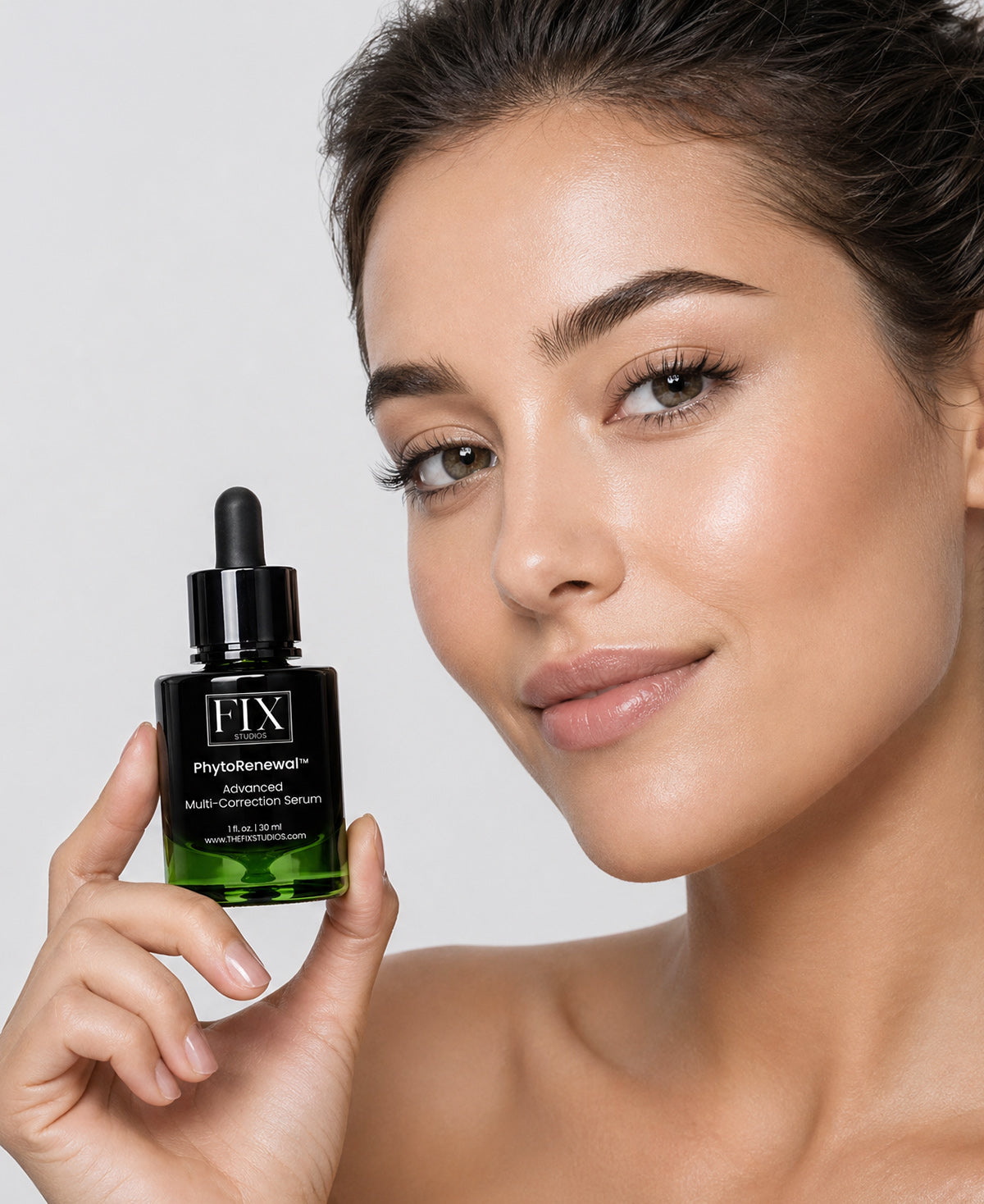 A woman holds a bottle of Fix Studios medical-grade PhytoRenewal™ Advanced Multi-Correction Serum to calm and soothe the skin after a laser or microneedling treatment