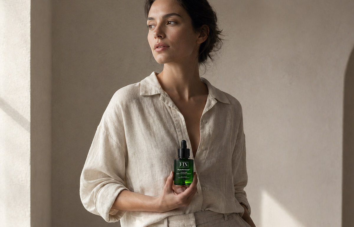A beautiful woman poses with soft perfect skin and holding a bottle of Fix Studios medical-grade PhytoRenewal™ Advanced Multi-Correction Serum
