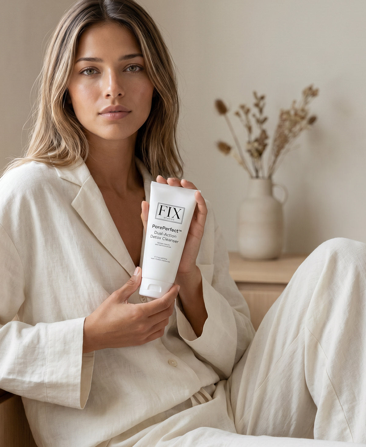 A woman holds a bottle of Fix Studios medical-grade PorePerfect™ Dual-Action Detox Cleanser balanced hydration